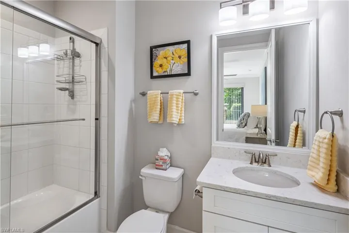 Full bathroom featuring shower / bath combination with glass door, vanity with extensive cabinet space, crown molding, and toilet