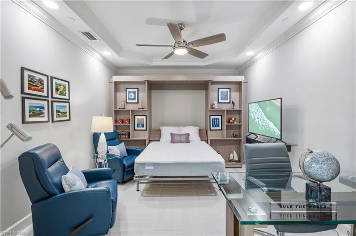 Tiled bedroom featuring ornamental molding, ceiling fan, and a raised ceiling