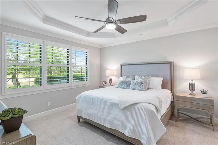 Bedroom featuring ceiling fan, ornamental molding, a tray ceiling, and carpet floors