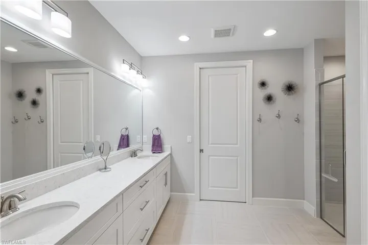 Bathroom featuring a shower with door, tile flooring, oversized vanity, and double sink