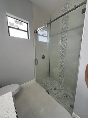 Bathroom featuring toilet, tile patterned flooring, and an enclosed shower