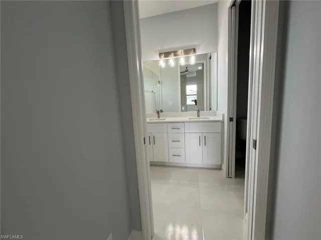 Bathroom with tile patterned flooring, toilet, and dual bowl vanity
