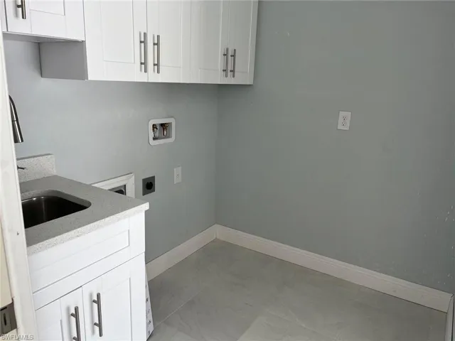 Laundry area with cabinets, washer hookup, sink, light tile floors, and hookup for an electric dryer