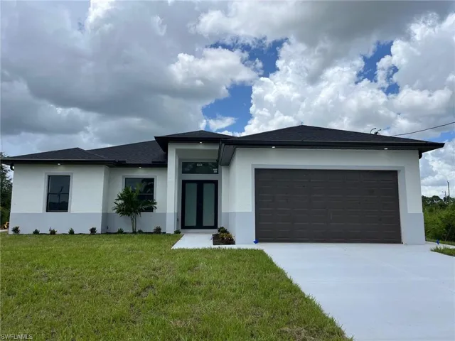 View of front of home with a garage and a front lawn