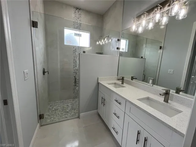 Bathroom featuring walk in shower, tile patterned flooring, and double sink vanity