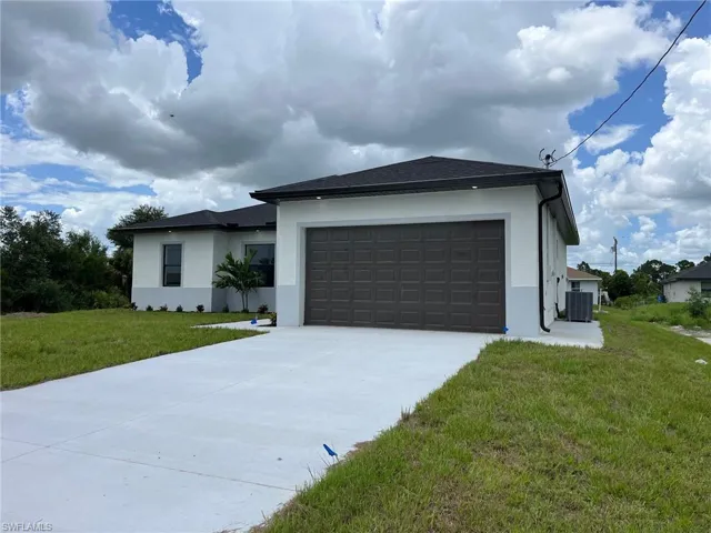 View of front facade featuring a garage, cooling unit, and a front lawn