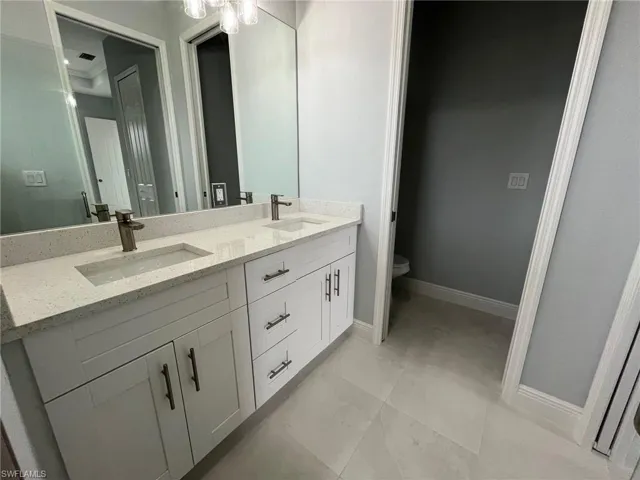 Bathroom featuring dual vanity, tile patterned floors, and toilet