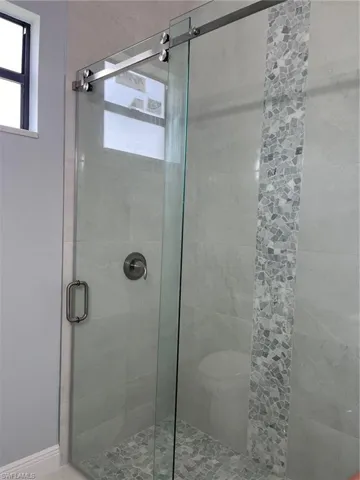 Bathroom featuring a shower with shower door and toilet