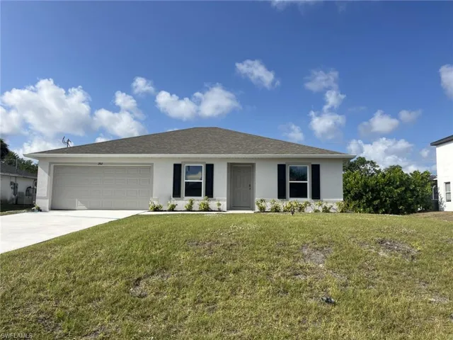 Ranch-style home featuring stucco siding, a front lawn, driveway, an attached garage, and roof with shingles