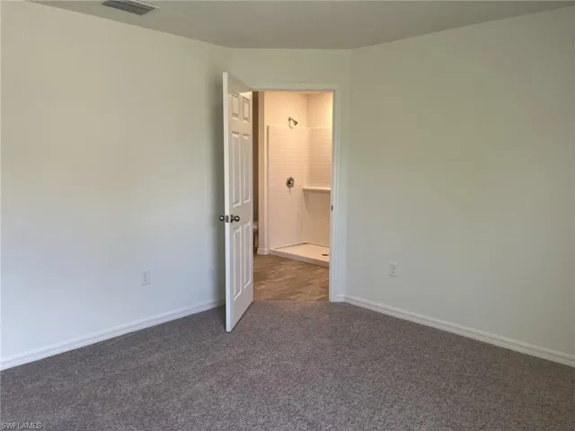 Empty room featuring dark colored carpet and baseboards