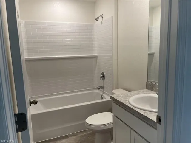Full bath with vanity, shower / tub combination, wood tiled floors, and a textured wall