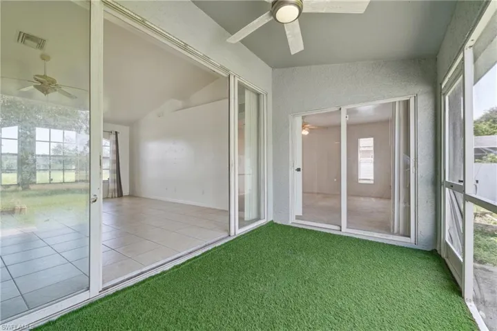 Screened-in patio with artificial turf flooring, featuring a ceiling fan, and multiple sets of sliding glass doors