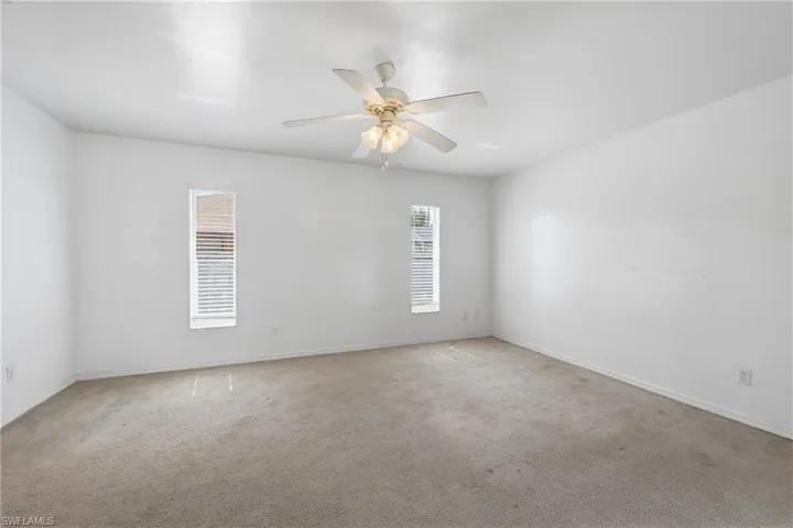 Recessed windows featuring blinds, ceiling fan with integrated lighting, and neutral carpeting