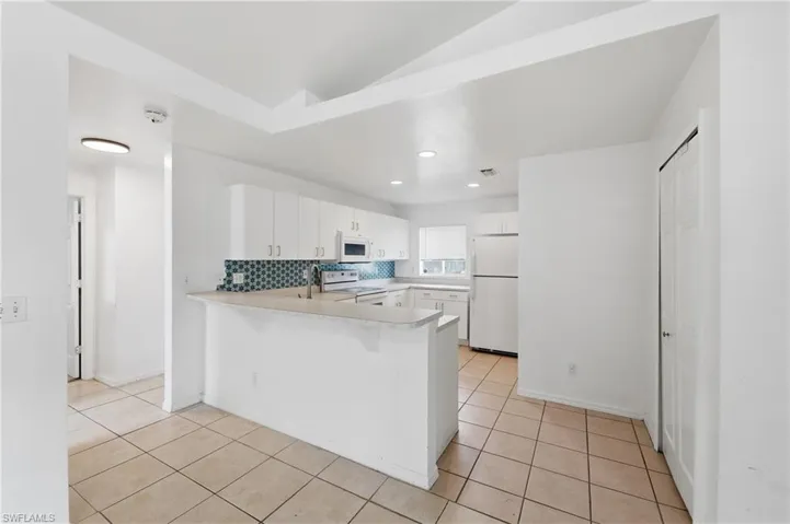 Kitchen featuring white cabinetry, tile backsplash, stainless steel appliances, and a breakfast bar