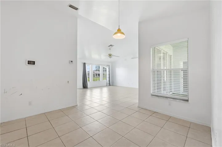 Vaulted ceiling, tiled flooring, window with blinds, pendant light fixture, ceiling fan