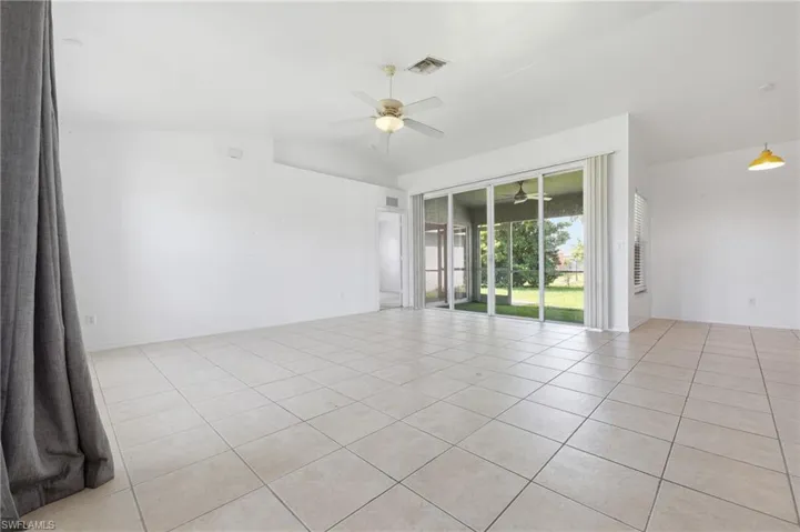 Vaulted ceiling, ceiling fan, tiled flooring, sliding glass doors, and screened-in patio