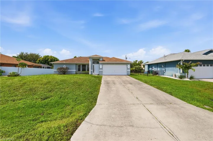 Single-story residence featuring a two-car garage, concrete driveway, and a manicured lawn
