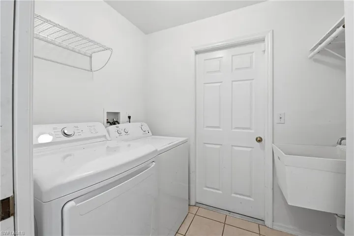 Utility room with a built-in wire shelf, tiled flooring, and a wall-mounted utility sink