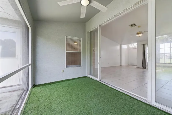 Screened patio featuring artificial turf flooring and a ceiling fan