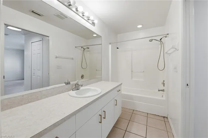 Vanity with an integrated sink, polished chrome faucet, and expansive wall-mounted mirror