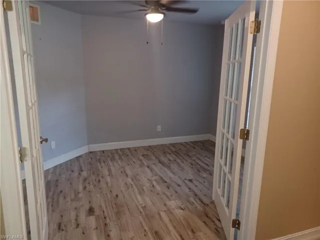 Empty room featuring wood finished floors, a ceiling fan, and french doors