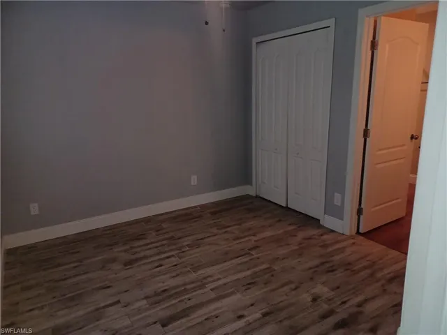 Unfurnished bedroom featuring dark wood-type flooring and a closet
