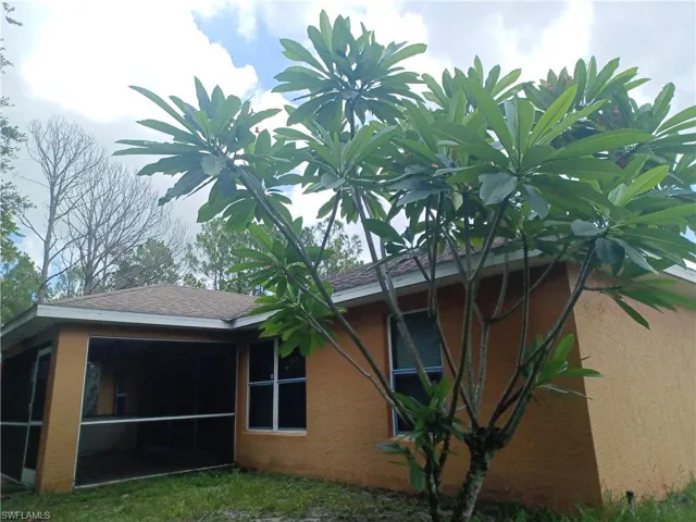 View of home's exterior with a sunroom, stucco siding, and roof with shingles