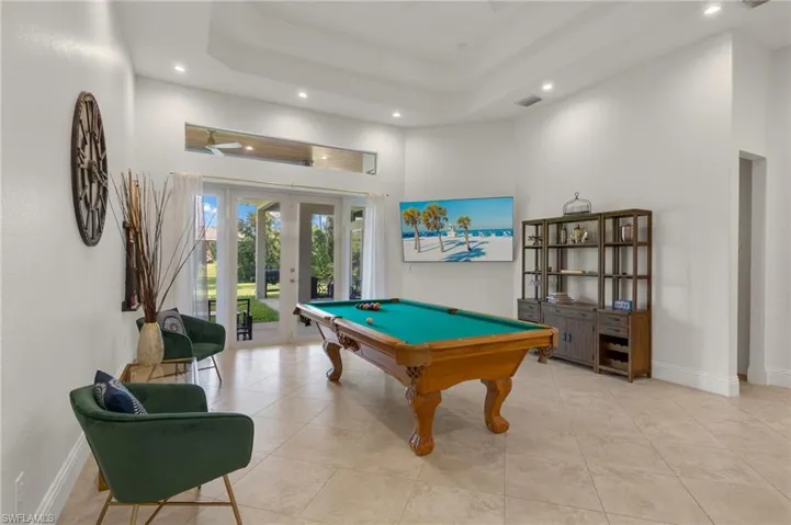 Game room featuring billiards, light tile patterned floors, french doors, a raised ceiling, and a high ceiling