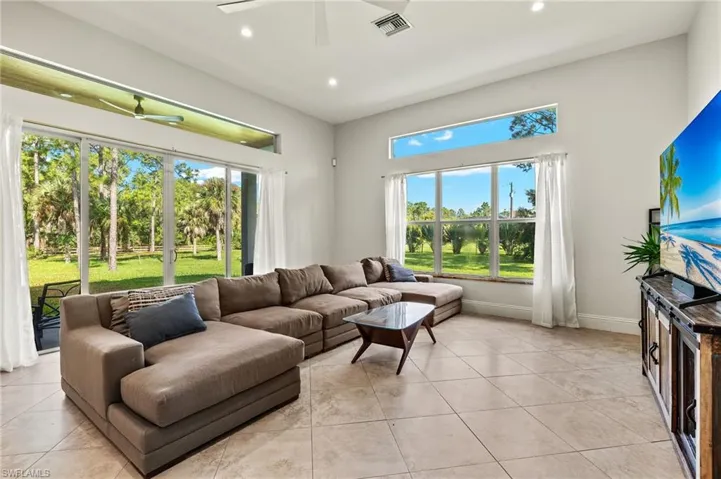Living room featuring ceiling fan, light tile patterned floors, and a healthy amount of sunlight