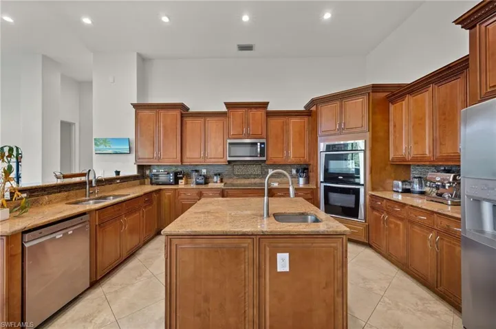 Kitchen with a kitchen island with sink, appliances with stainless steel finishes, backsplash, and sink