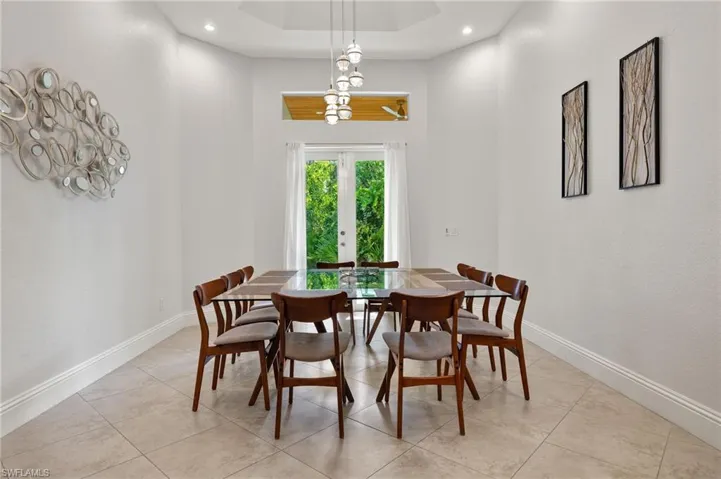 Tiled dining area featuring a raised ceiling and french doors
