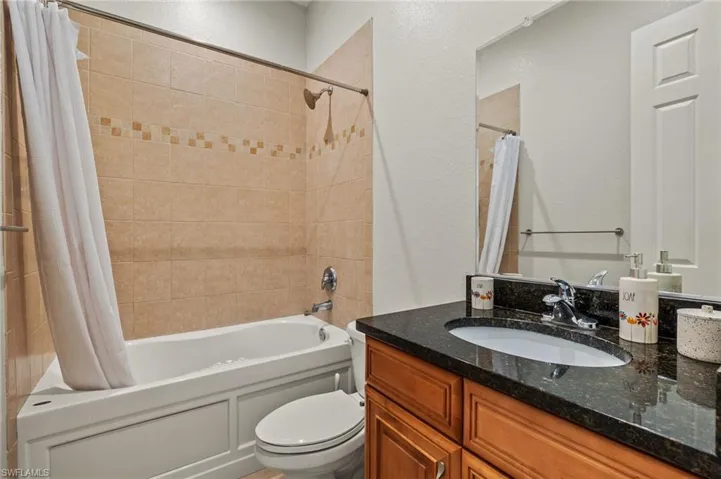 Full bathroom with toilet, shower / tub combo with curtain, and vanity