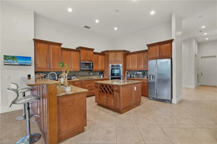 Kitchen featuring a kitchen bar, kitchen peninsula, light stone counters, and appliances with stainless steel finishes