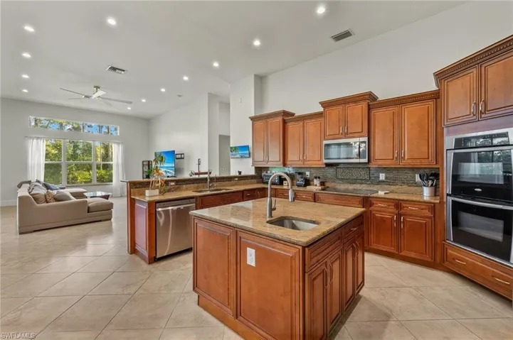 Kitchen featuring a kitchen island with sink, stainless steel appliances, sink, kitchen peninsula, and ceiling fan