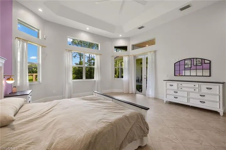Tiled bedroom with a high ceiling, a tray ceiling, and ceiling fan