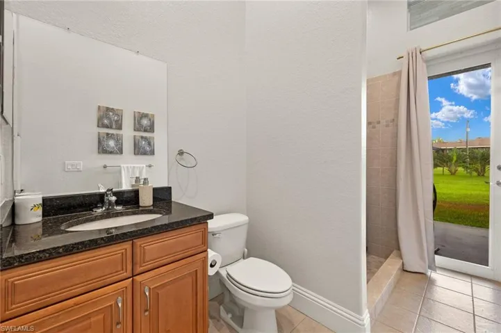 Bathroom with vanity, toilet, walk in shower, and tile patterned flooring