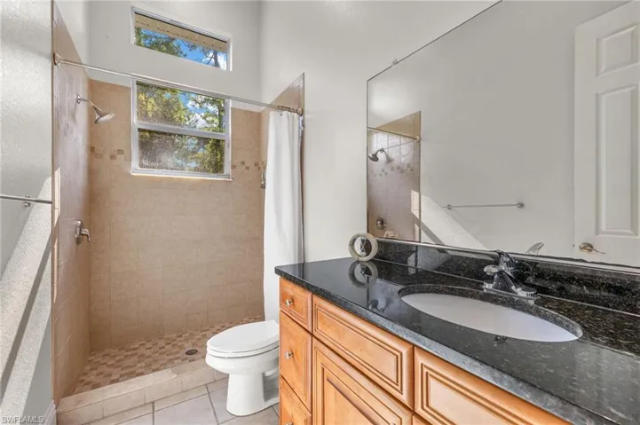 Bathroom with tile patterned floors, a shower with shower curtain, toilet, and vanity