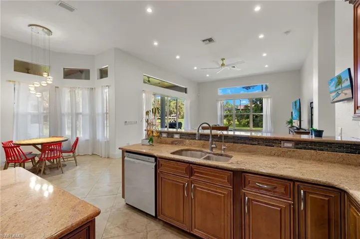 Kitchen featuring hanging light fixtures, light stone countertops, sink, ceiling fan, and stainless steel dishwasher