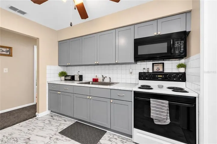 Kitchen featuring gray cabinetry, white square tile backsplash, white countertops, and wood-finish ceiling fan