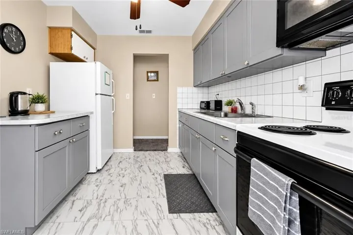 Contemporary kitchen featuring shaker-style cabinetry, white countertops, and a white tile backsplash