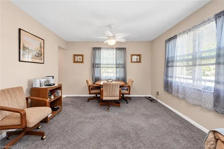 Carpeted room featuring a ceiling fan, window blinds, and multiple windows