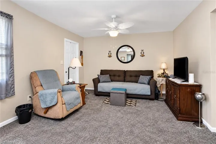 Neutral wall color, carpeted flooring, ceiling fan with light fixture, and white interior door