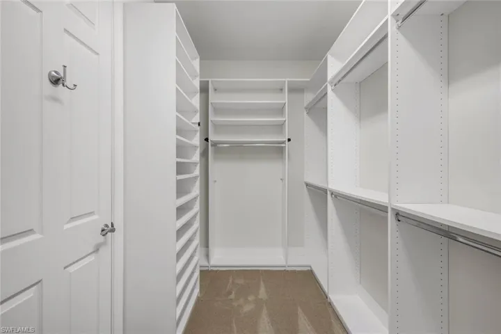 Walk-in closet with built-in shelving, multiple hanging rods, and neutral-toned carpeting