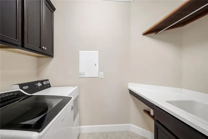 Laundry area featuring dark wood-finish cabinetry, white countertop, and a built-in sink