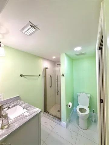 Bathroom featuring vanity, light marble finish flooring, and a marble finish shower