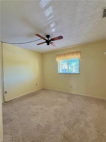 Carpeted spare room featuring a textured ceiling and a ceiling fan