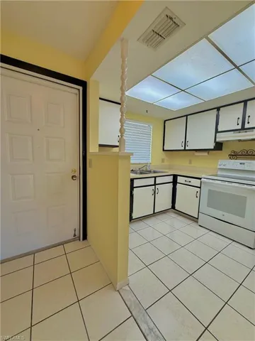 Kitchen featuring white cabinets, white range with electric cooktop, light countertops, and light tile patterned flooring