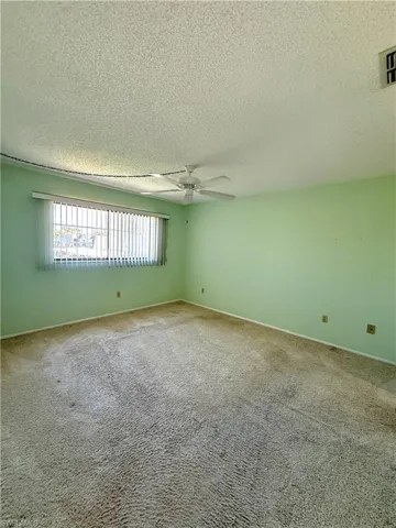 Carpeted empty room featuring a ceiling fan and a textured ceiling