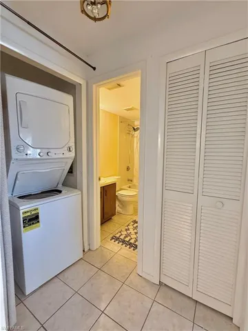 Laundry area featuring stacked washing machine and dryer and light tile patterned floors
