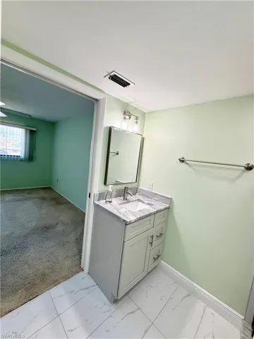 Bathroom with vanity, light colored carpet, and light marble finish flooring
